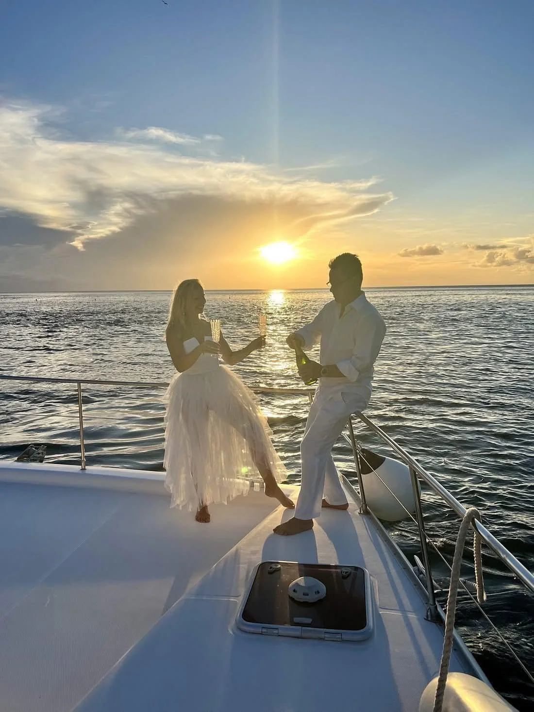 Couple celebrating with champagne on the bow during a St. Lucia sunset cruise